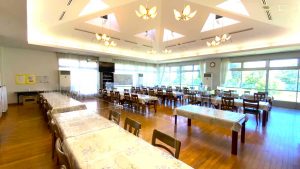 天井照明が美しい広々とした食堂。複数のテーブルと椅子が配置された明るい空間